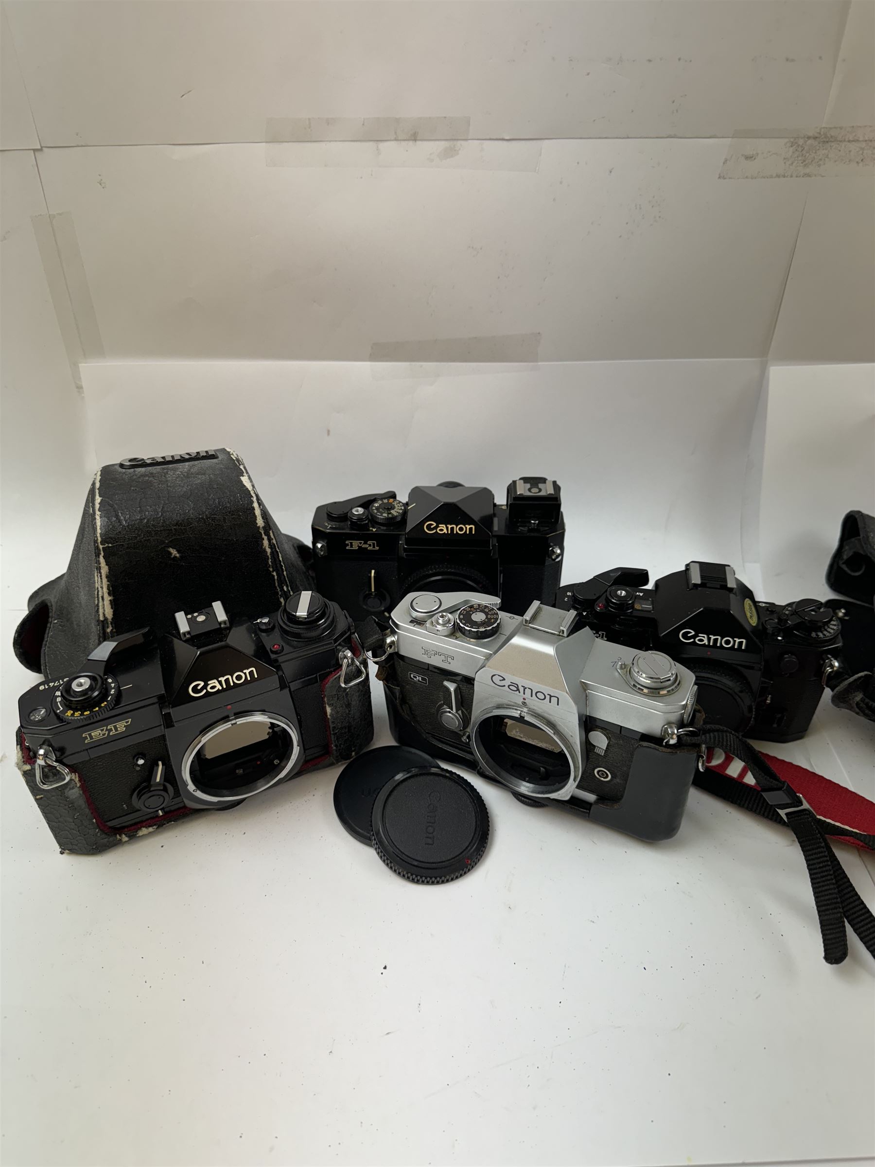 Four Canon SLR camera bodies, to include F-1 serial no. 273243, A-1 serial no. 1818620, EF serial no. 317419, all in black finish, with Canon cases, and an FT serial no. 251226 in black and silver finish