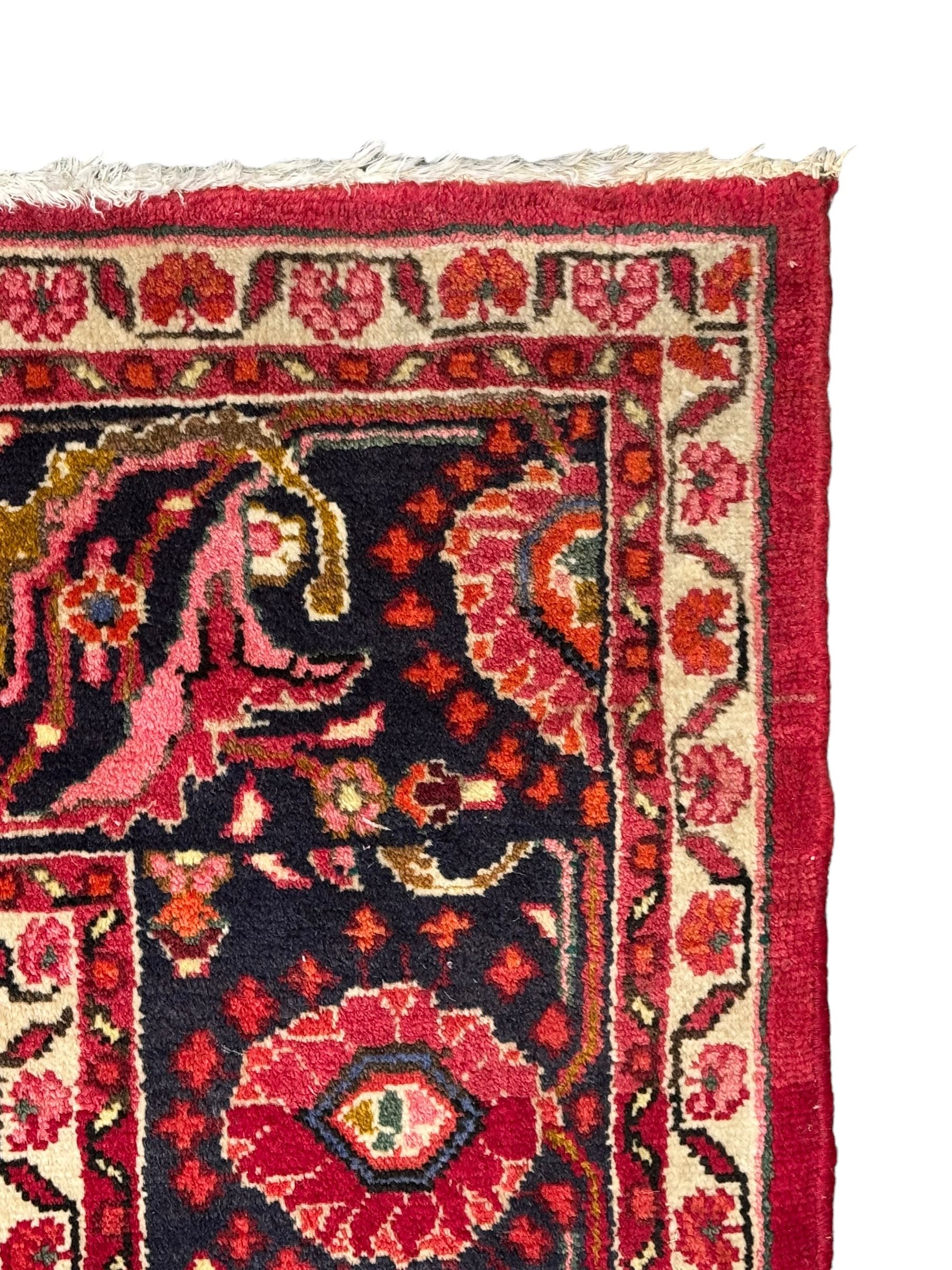 Persian Nanaj crimson ground carpet, the busy field filled with interconnecting stylised plant motifs with scrolling branches, the guarded indigo border decorated with repeating palmettes and foliate patterns