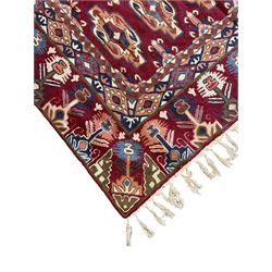 Caucasian design crewelwork hanging, crimson ground, the field decorated with geometric designs, the wide guard band with repeating stylised plant  motifs