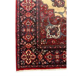 North East Persian Meshed carpet, the field with large central medallion decorated with stylised plant motifs, the field surrounded by panels, medallions and spandrels decorated with floral motifs, indigo ground border with overall floral design 