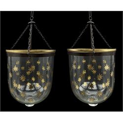 India Jane Interiors - pair of glass hanging lanterns, clear glass bell jars decorated with gold starburst patterns, each topped with a wide glass dish and suspended by three brass chains, the rim of each bell jar accentuated with a brass band, black metal hooks with a dragon head motif attach the chains to the rim