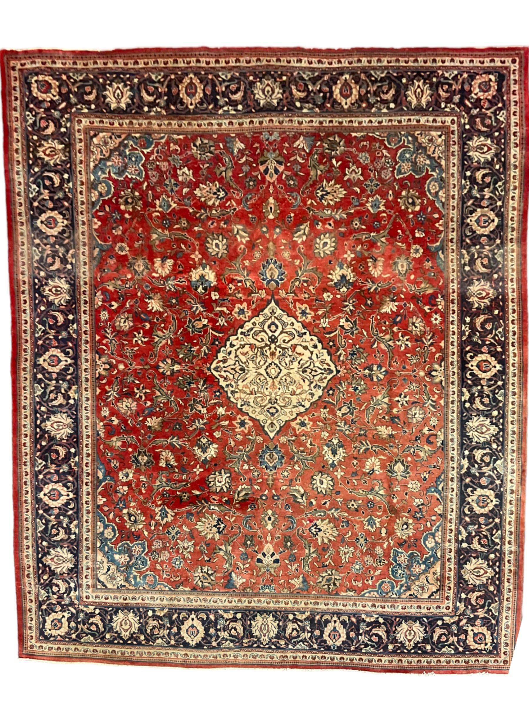 Persian Kashan crimson ground carpet, central shaped pale ground medallion surrounded by interlacing branches and stylised floral motifs, indigo main border with scrolling foliage design, within guard stripes 