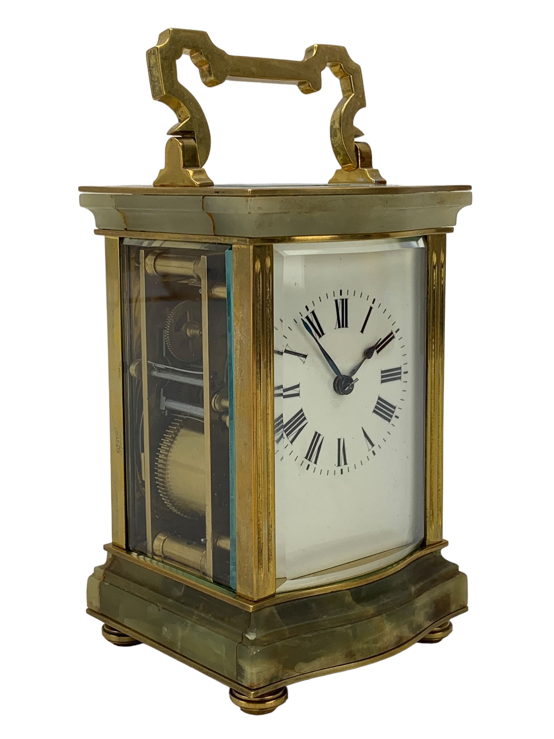 French - early 20th century two train carriage clock, in an onyx serpentine case raised on bun feet, with four bevelled panels and rectangular escapement viewing panel, white enamel dial with Roman numerals and steel spade hands, 8-day movement with a jewelled lever platform escapement and rack striking, sounding the hours and half hours on a coiled gong. With key.