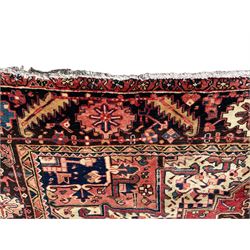 Persian Heriz red ground carpet, large central eight point medallion with projecting palmettes surrounded by small geometric motifs, decorated profusely with hooks, rosettes and animals, the busy border decorated with stylised foliate motifs within guard stripes 