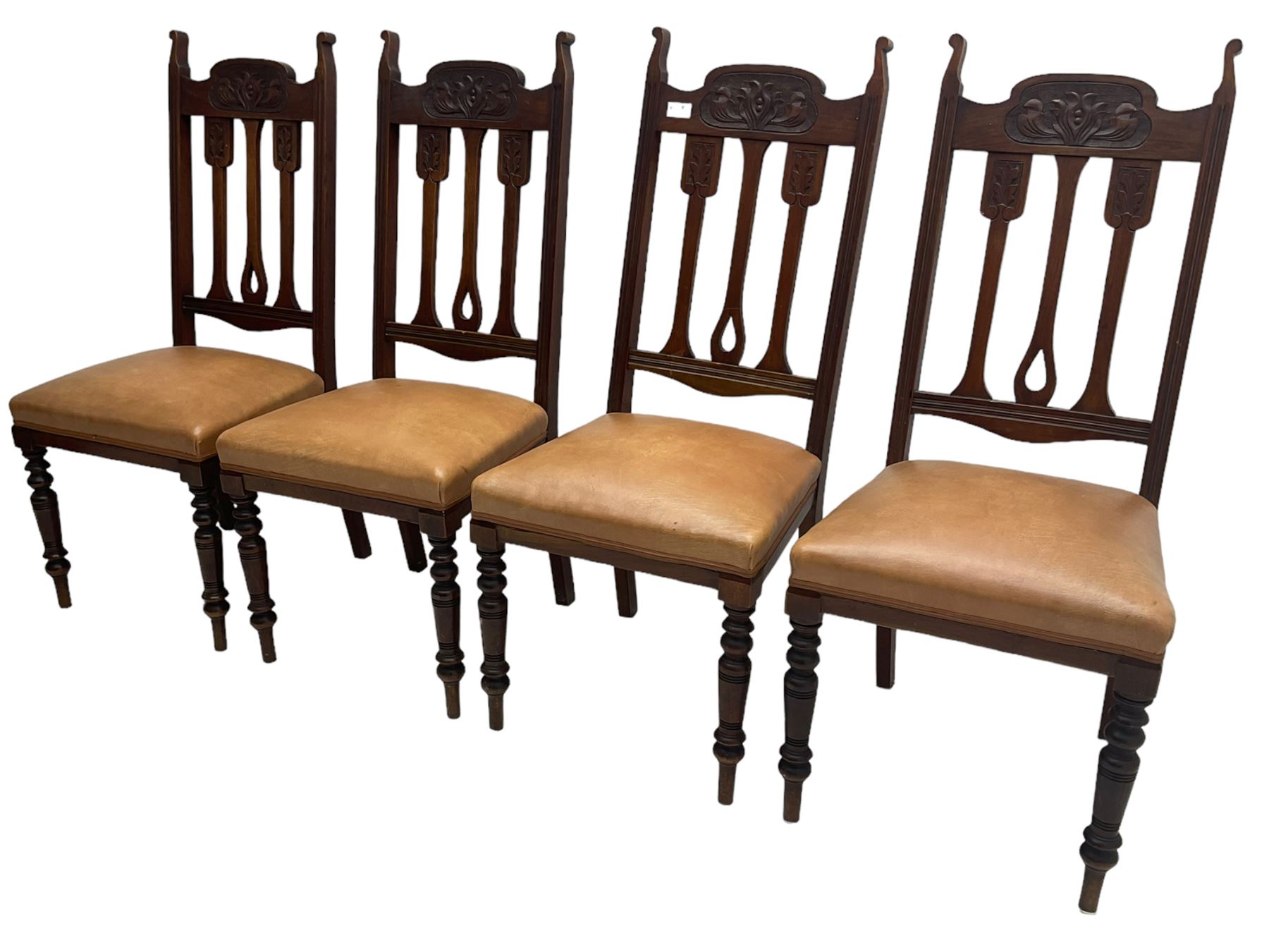 Set of four Edwardian walnut dining chairs, foliate carved high back over sprung seat upholstered in tan faux leather, raised on turned supports