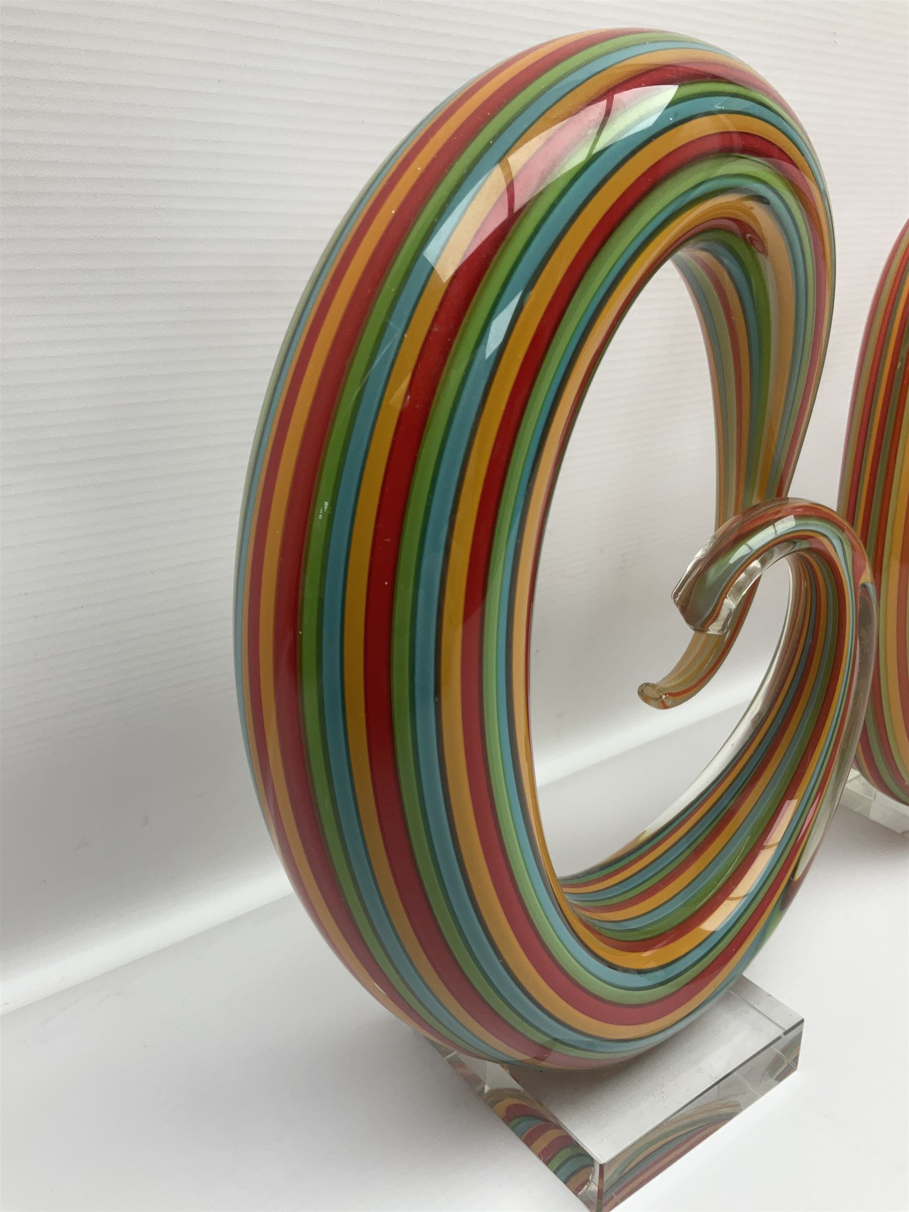 Three art glass sculpture, coiled form with multicolour stranded, upon clear glass plinth, unsigned, largest H27cm