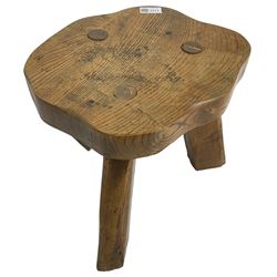 Small rustic elm three-legged stool, with metal plaque to the underneath inscribed 'Wandewood' 