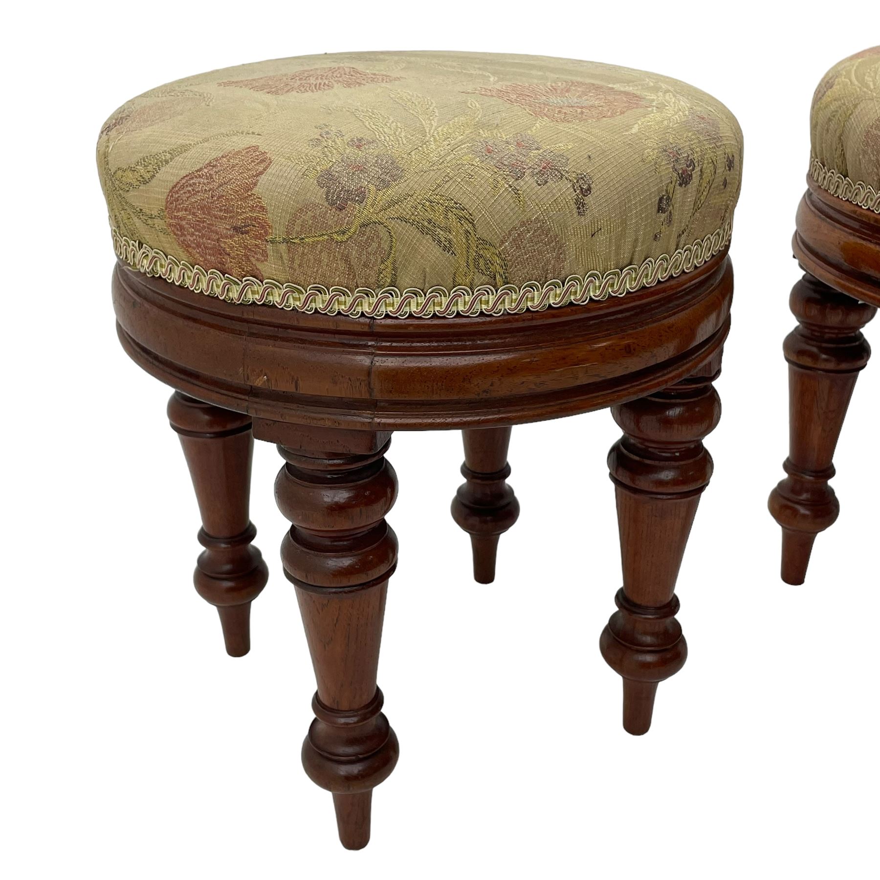 Pair of Victorian walnut circular stools, cushioned seats upholstered in floral pattern fabric, moulded seat rail over turned supports 