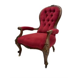 Victorian walnut open armchair, the cresting rail carved with flower heads and extending foliage, upholstered in buttoned red leather, scrolled arms and cabriole supports carved with flowers