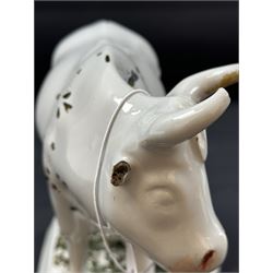 19th century Delft figure group depicting a milkmaid milking a cow, H17.7cm