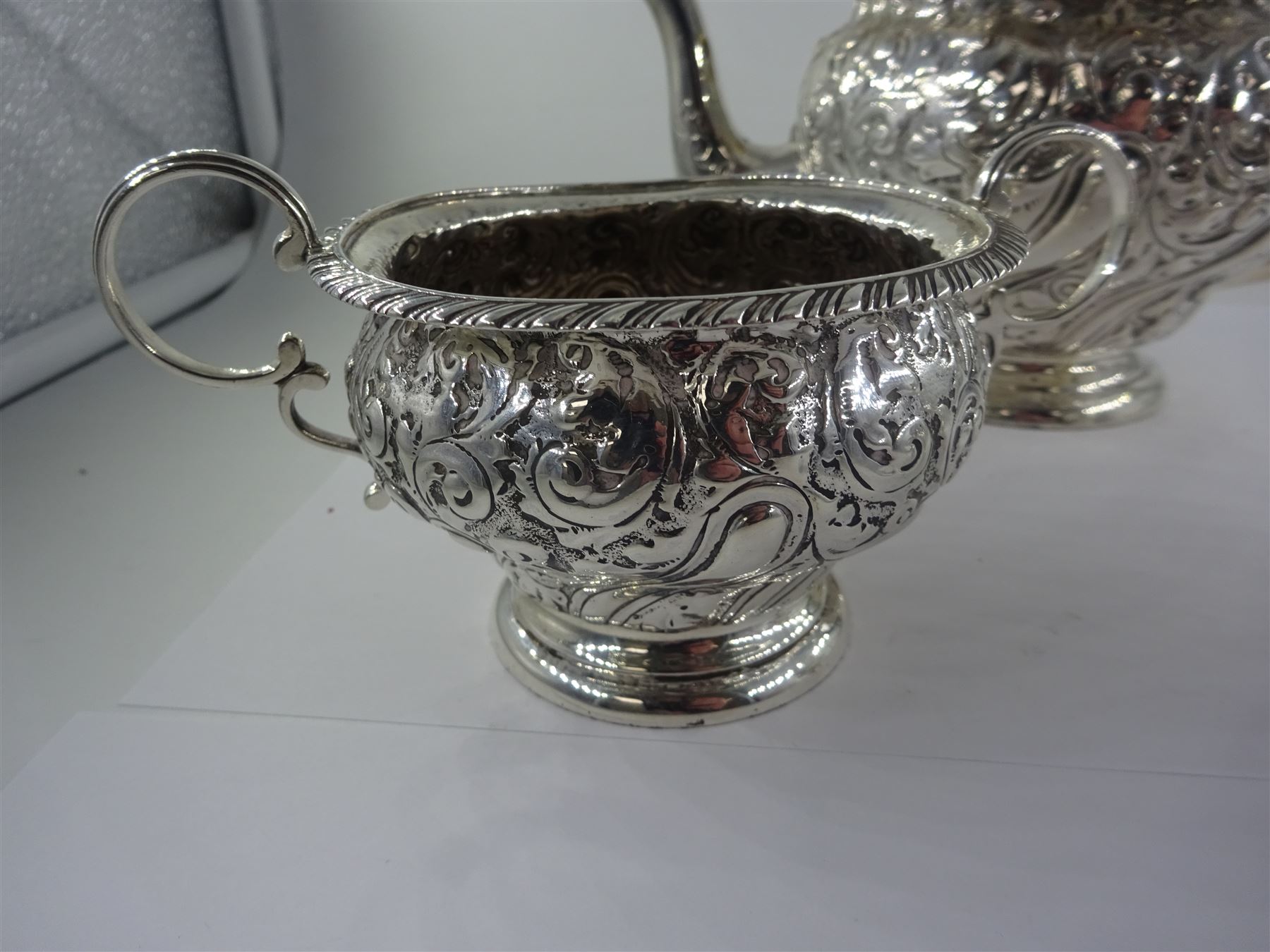 Late Victorian silver three piece bachelors tea service, comprising teapot, open sucrier and milk jug, each of bellied form, upon a circular stepped foot, and profusely embossed with foliate and scrolling decoration, the teapot with ebonised handle and finial, hallmarked George Nathan & Ridley Hayes, Birmingham 1894, teapot H14.5cm