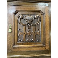 Arts & Crafts period oak corner cabinet, projecting cornice over astragal glazed door and single panelled door decorated with applied carved foliate scrolls and stylised roods surrounded by moulded edge, enclosing single shelf