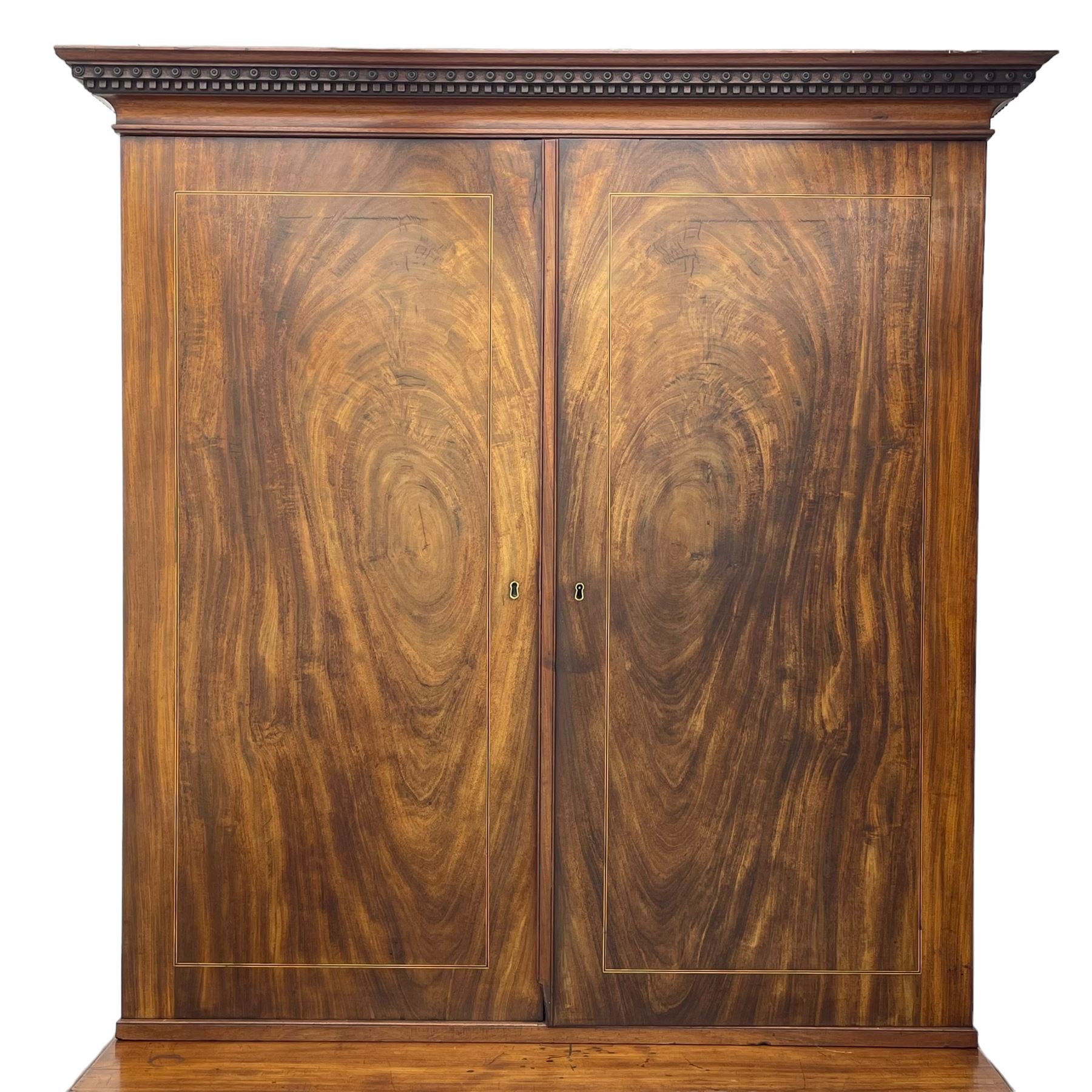 George III figured mahogany secretaire bookcase, projecting moulded dentil cornice decorated with single row of roundels, two figured mahogany doors with boxwood and ebony stringing enclosing three adjustable shelves and three drawers, moulded rectangular top over four long scratch-moulded drawers, the top secretaire drawer with fall front enclosing small drawers, pigeon holes and inset writing surface, shaped apron with bracket feet