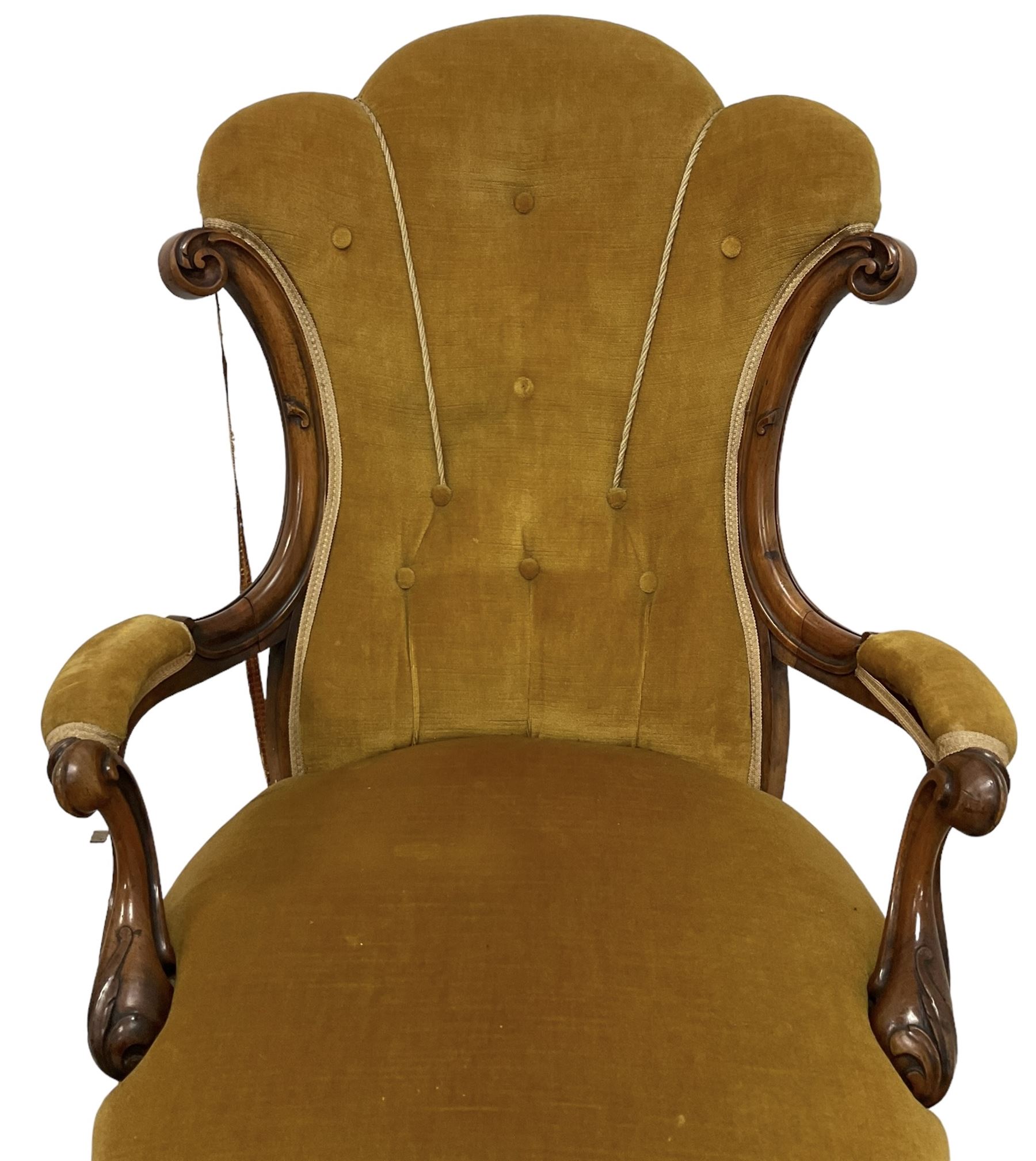 19th century walnut framed open armchair, scallop shaped back with c-scroll uprights, upholstered in yellow buttoned velvet fabric with sprung seat, arm terminals carved with acanthus leaves, raised on scrolling cabriole supports with castors