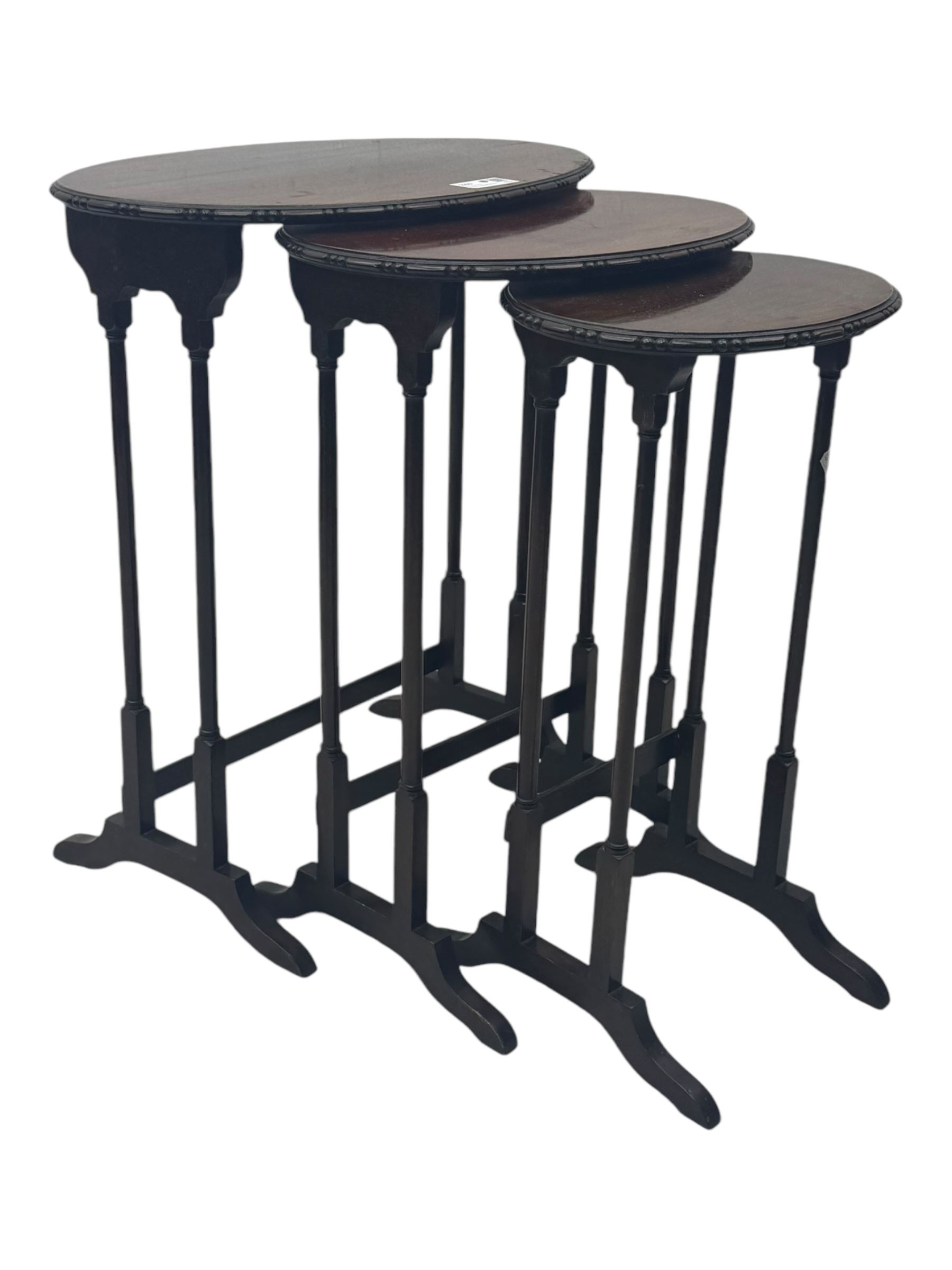 Early 20th century mahogany nest of three tables, oval tops with carved edges, turned uprights with splayed feet united by cross stretchers