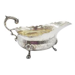 1930s silver sauce boat, of typical form with shaped rim, and acanthus leaf capped flying scroll handle, upon three palmette mounted stepped feet, hallmarked 	Harrods Ltd, London 1934, including handle H10.4cm