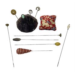 Ten Victorian and later hatpins, to include horseshoe examples, glass beads etc, together with two pin cushions 