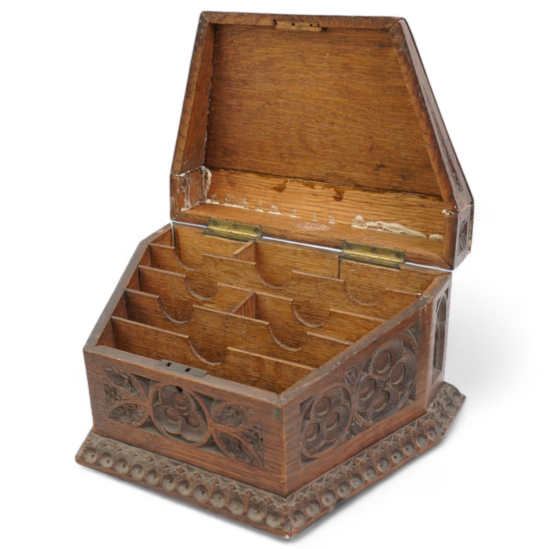 Late Victorian oak stationery box carved with Gothic and foliate panels, hinged sloping lid and divided interior with the trade label of H Ladd, 34 Trinity St. Cambridge, Stationer & Die Sinker W26cm