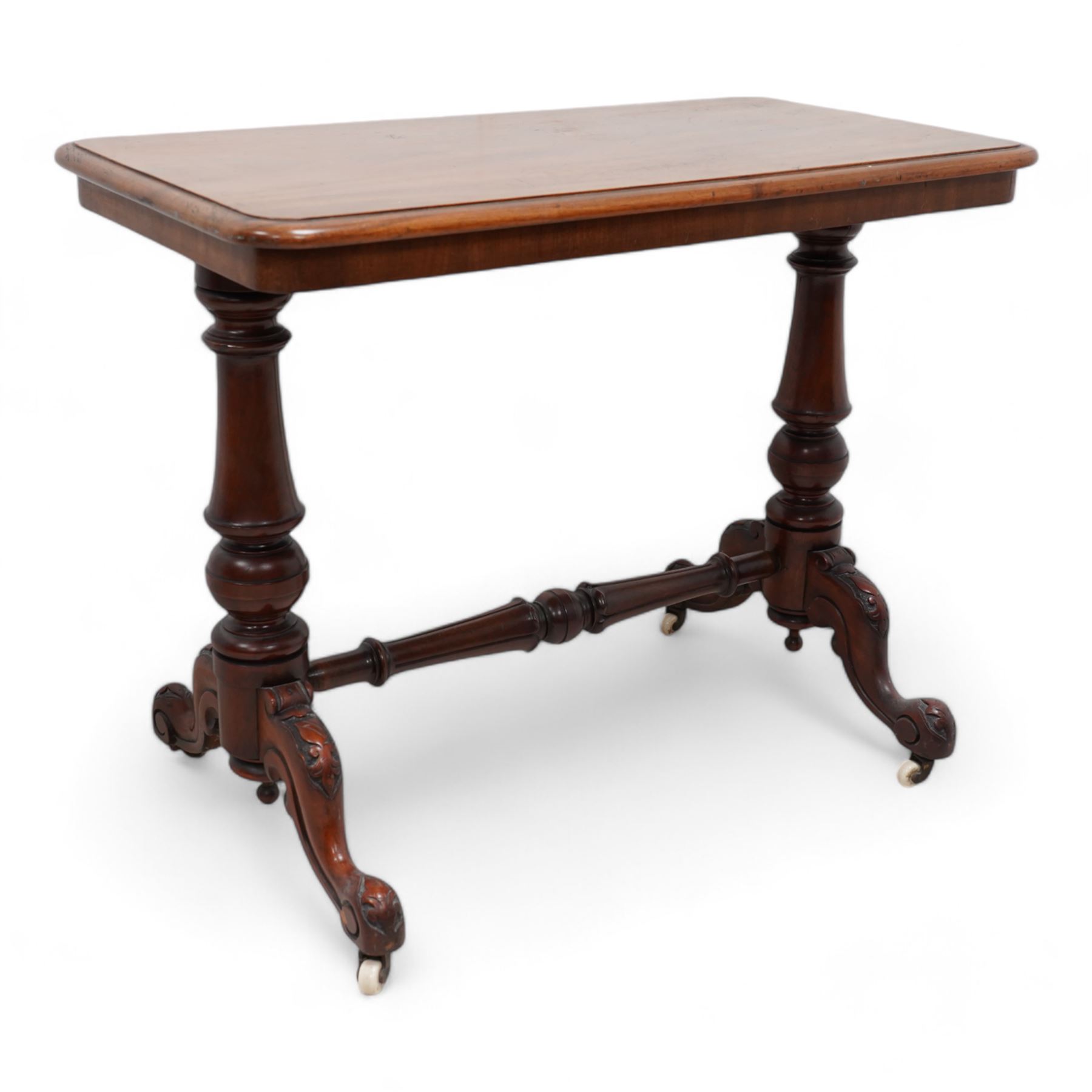 Victorian mahogany stretcher table, moulded rectangular top with rounded corners, on turned twin pillar supports united by turned and carved stretcher, on carved out splayed supports with brass and ceramic castors 