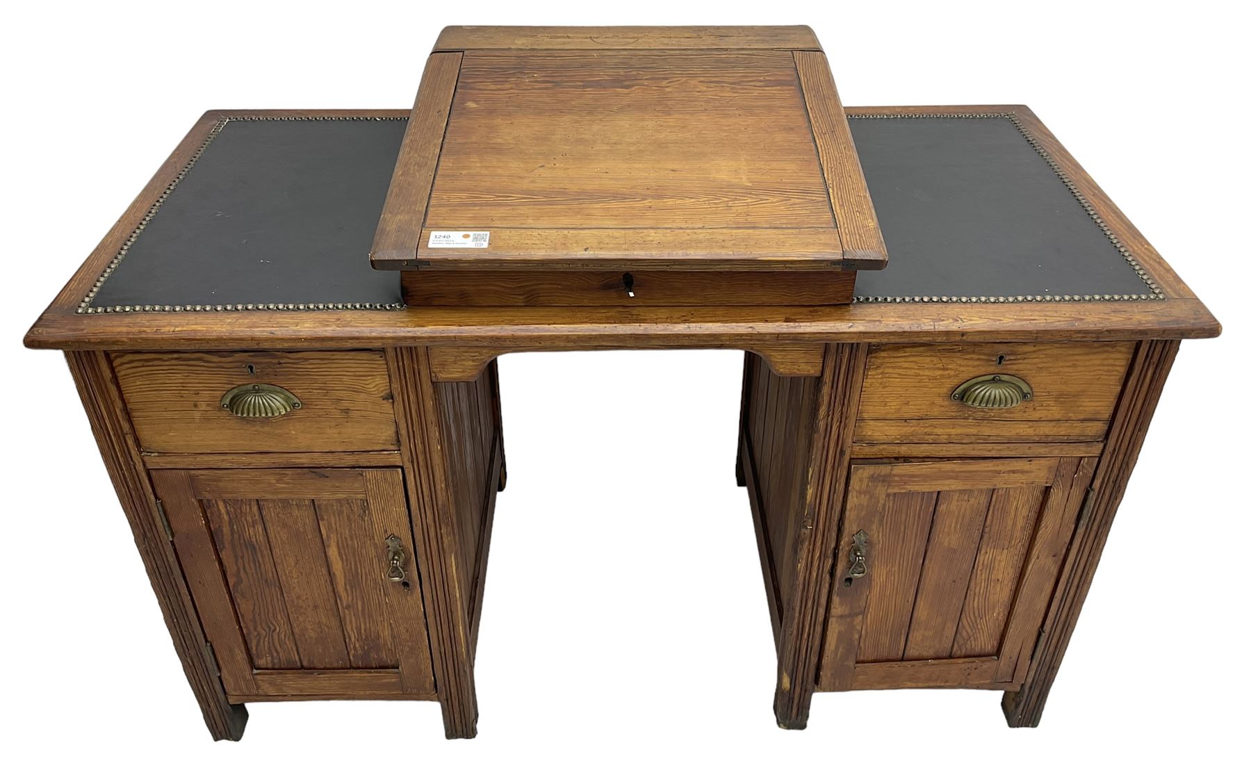 Edwardian pitch pine desk, rectangular top with writing slope flanked by inset leather writing surfaces, over twin pedestals each with shell cup handled drawer over cupboard, the left enclosing two shelves, the right enclosing sliding trays, on fluted straight supports