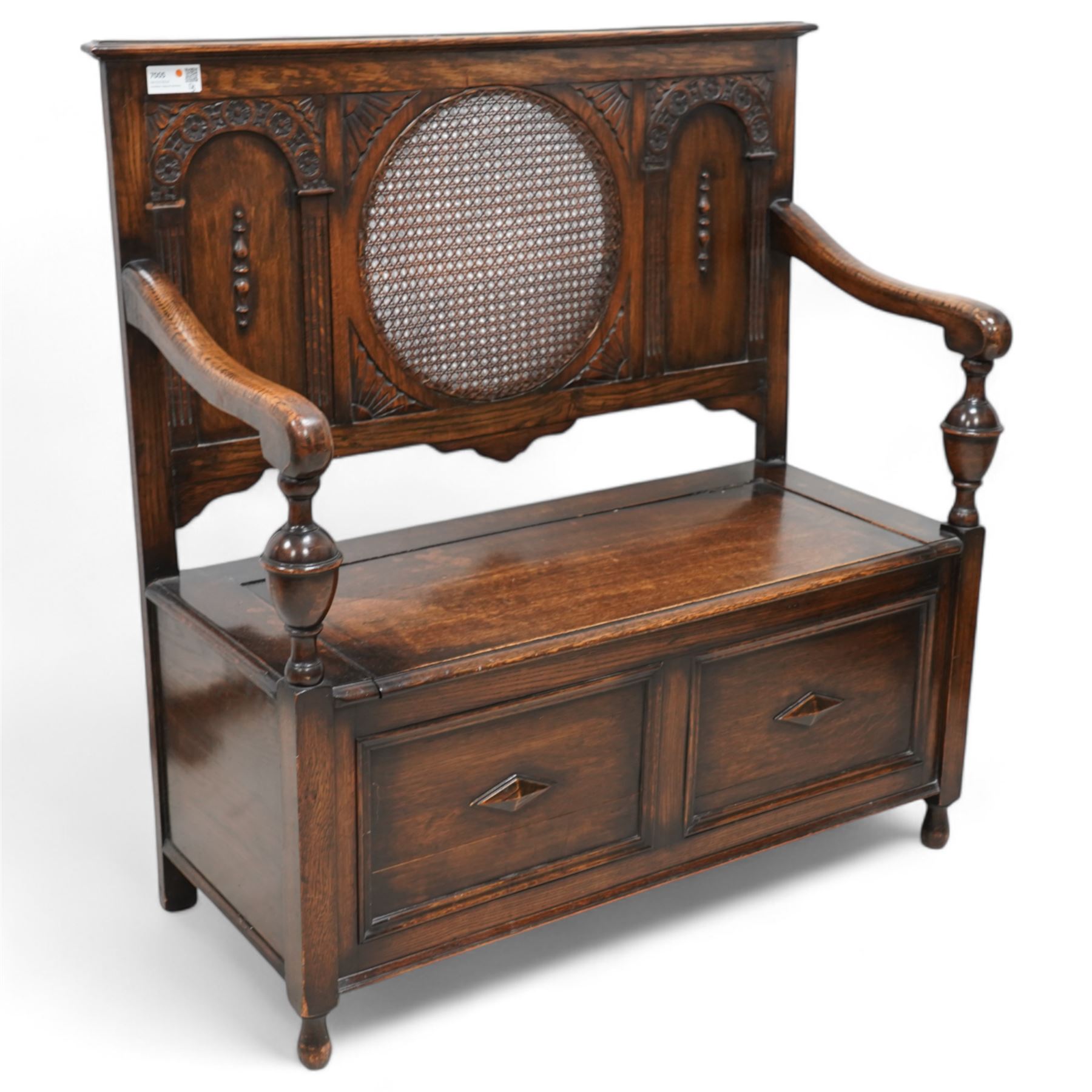 Early 20th century oak hall bench, circular caned back enclosed by panels decorated with flowerhead carved arcades, hinged box seat, panelled front 