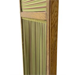 Edwardian oak and fabric folding screen, featuring three panels with oak frames, one side covered in green striped fabric with decorative trim, the reverse side in pink moiré effect fabric, connected by brass hinges