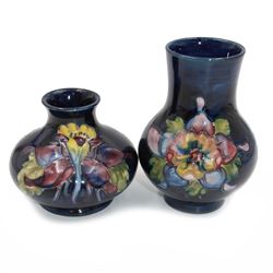 Two small Moorcroft vases decorated in Columbine pattern on dark blue ground, both with labels beneath, largest H11cm