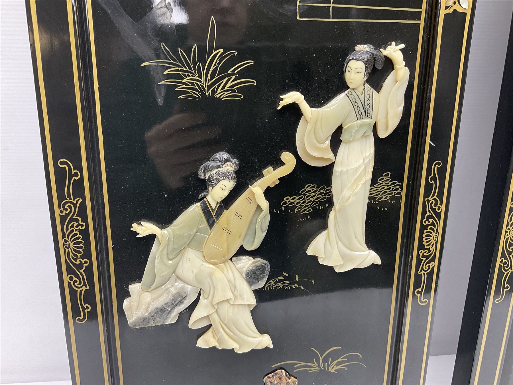 Two 20th century Chinese lacquered wall plaques, decorated in relief with female figures playing instruments beneath a pagoda, within gilt and mother of pearl inlaid borders, H92cm