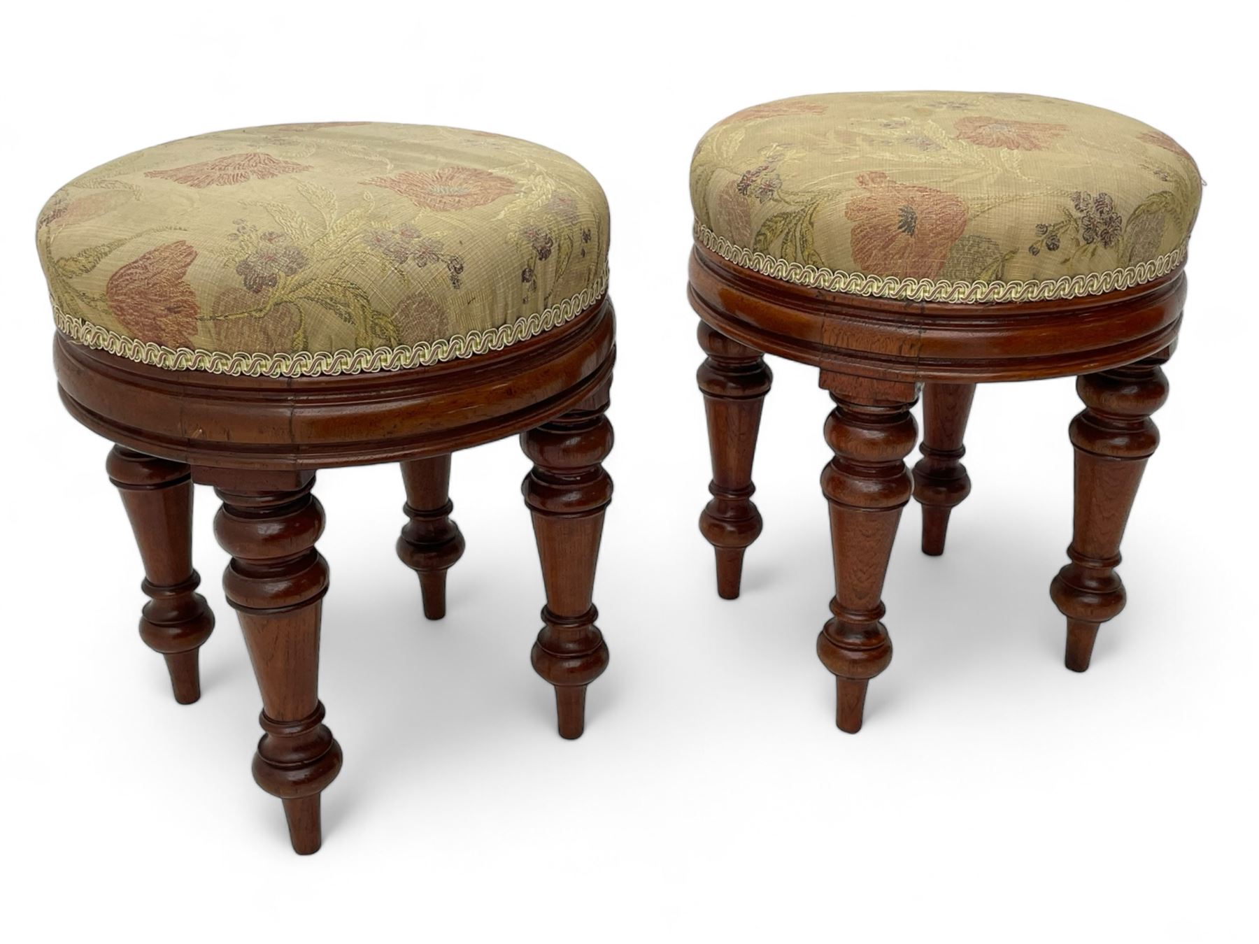 Pair of Victorian walnut circular stools, cushioned seats upholstered in floral pattern fabric, moulded seat rail over turned supports 