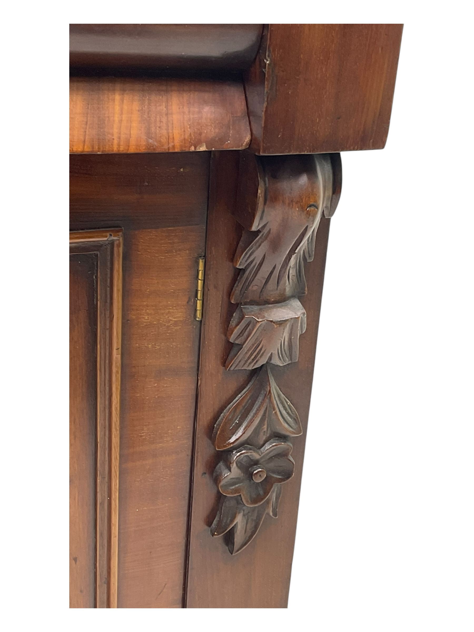 Mid 19th century mahogany sideboard, rectangular top over two frieze drawers with rounded edges, flanked by floral carved corbels, over two panelled cupboard doors, raised on a plinth base