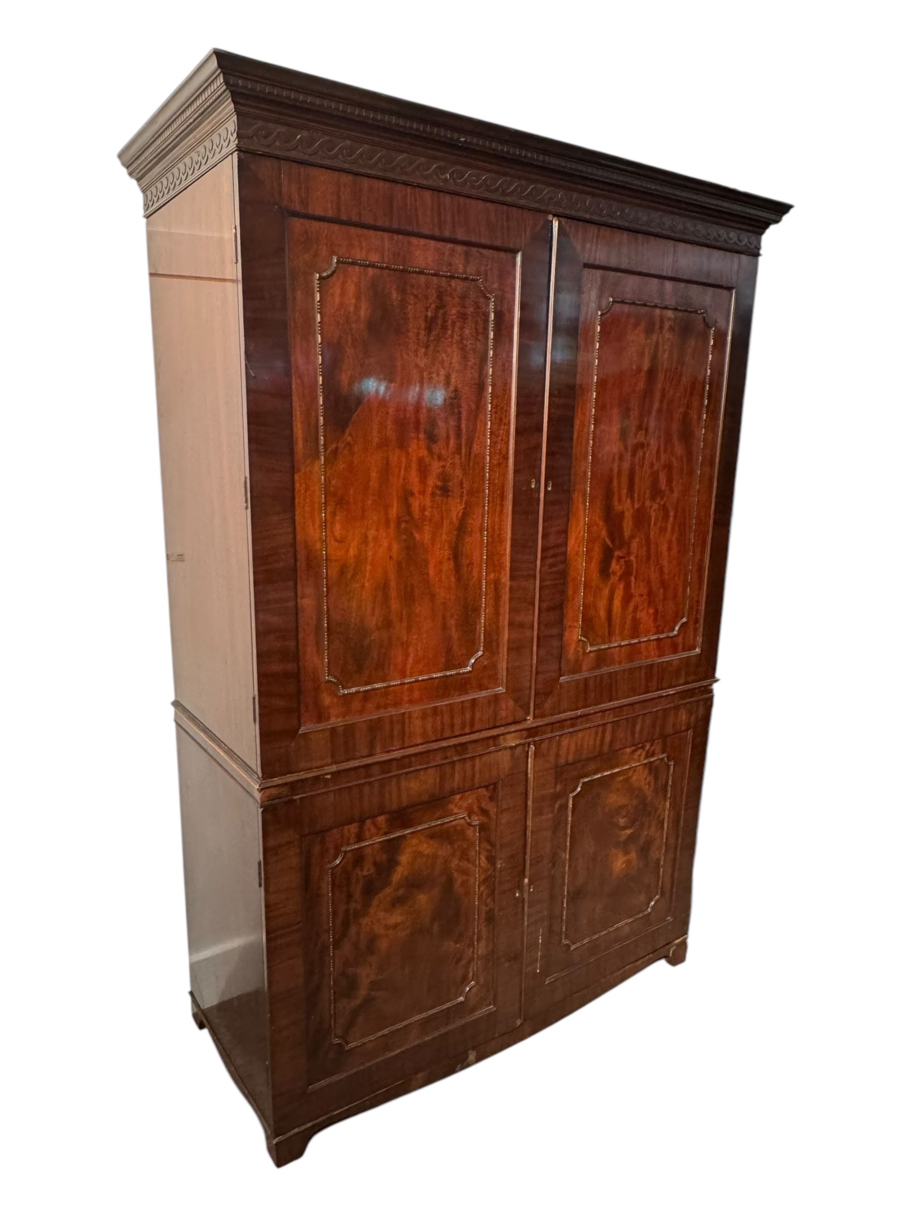 Victorian mahogany linen press, projecting cornice with dentil and scroll detailing, double panelled doors opening to an interior fitted with a brass hanging rail and coat hooks, lower section with two drawers and fitted shelves for additional storage, raised on bracket feet