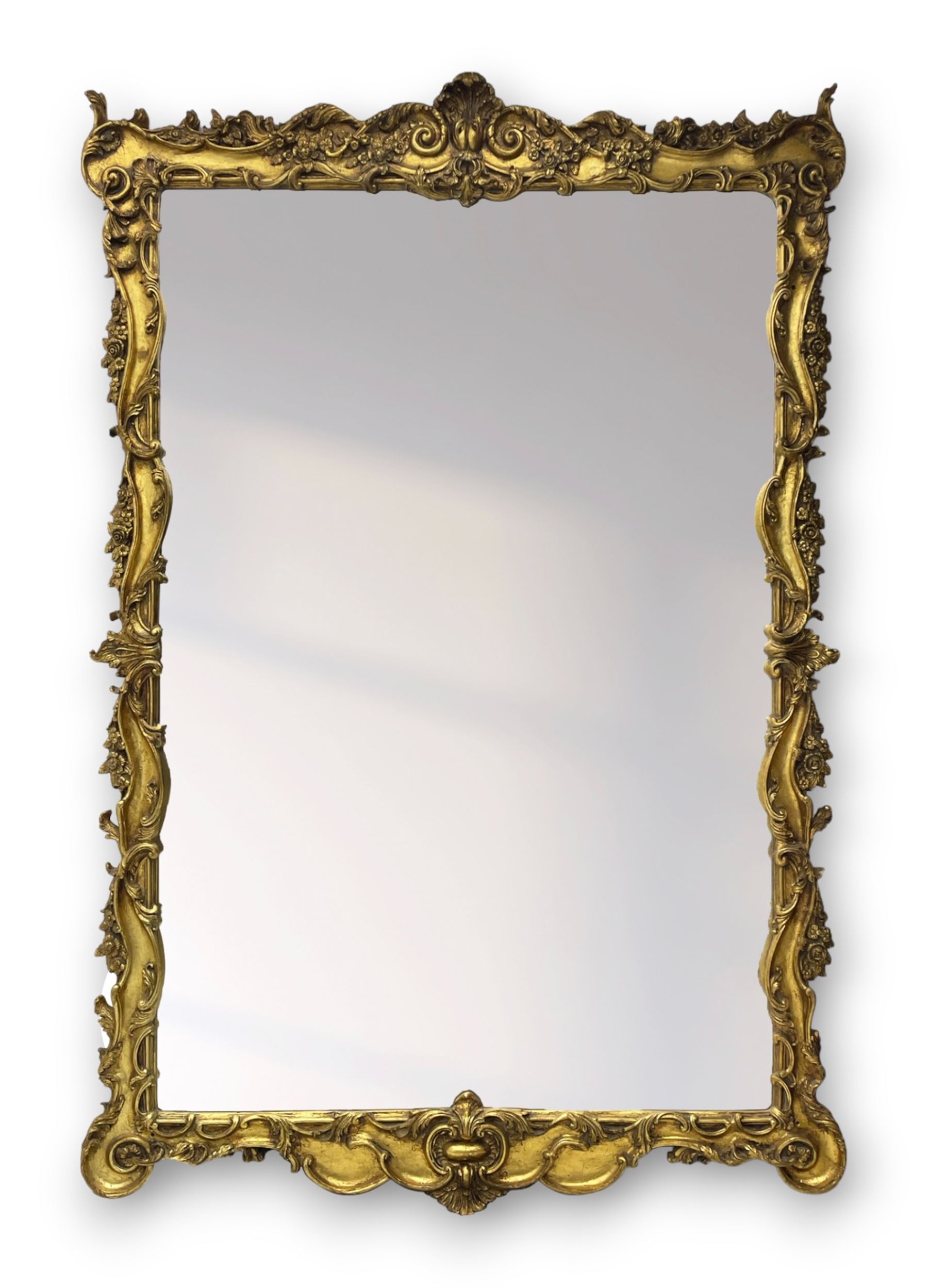 Large gilt framed rectangular wall mirror, shaped and moulded frame decorated with trailing curled acanthus leaves and flower head motifs, bevelled glass plate 