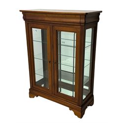 20th century cherry wood display cabinet, projecting cornice over two glazed doors with bevelled panes flanked by fluted support columns, enclosing three adjustable glass shelves with mirror-back surface, supported by shaped bracket feet