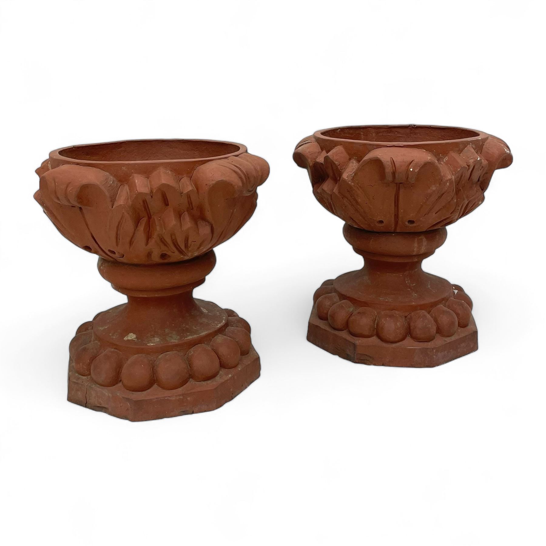 Pair of late 19th to early 20th century red terracotta garden urn planters, the shallow bowls moulded with curled acanthus leaf decoration, on circular foot with globular beaded moulding, octagonal base