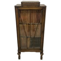 Edwardian oak bookcase, stepped top decorated with beading and stylised floral frieze, single astragal glazed door enclosing encyclopaedias and other books, on turned front feet united by plain stretchers 