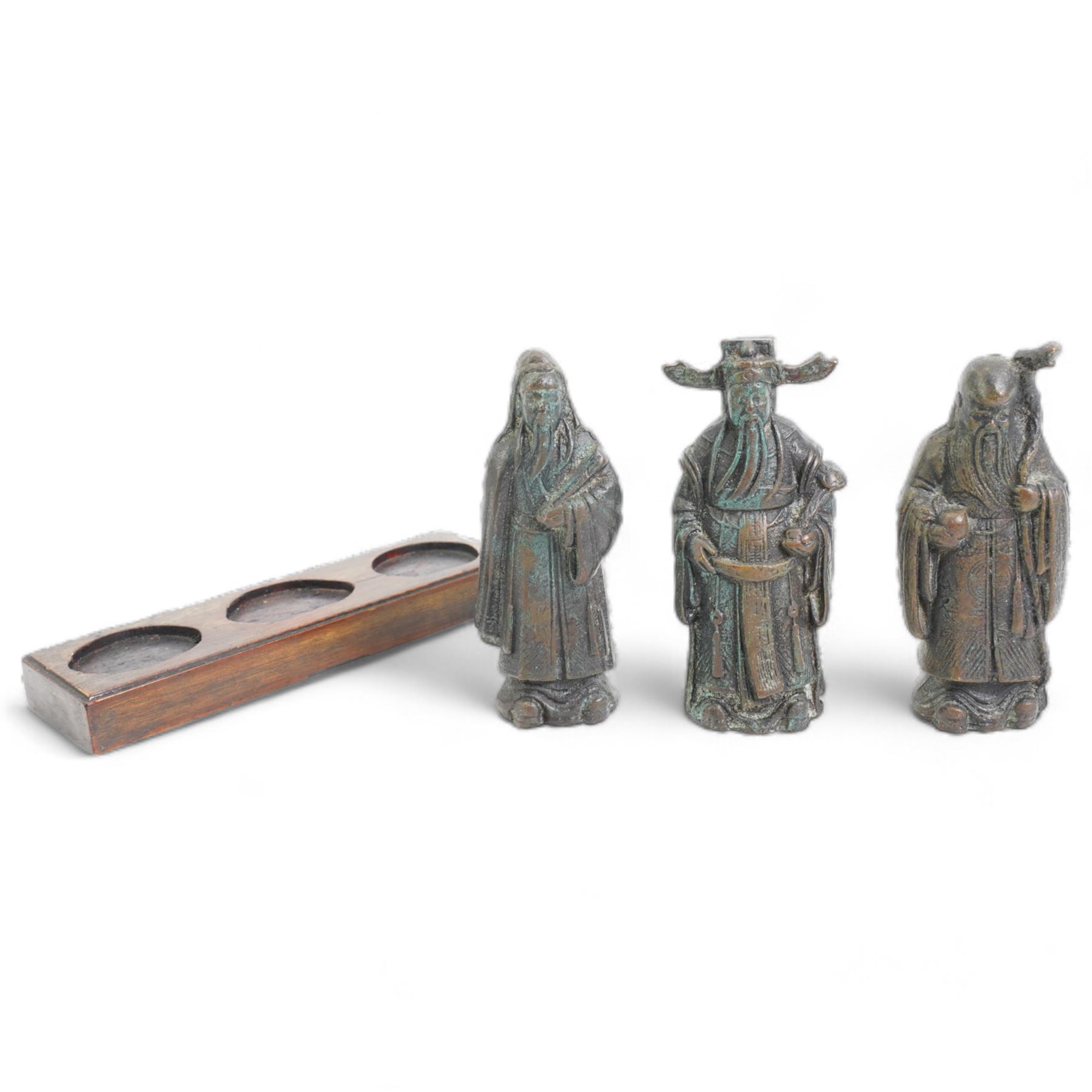 Set of three Chinese bronze deities, on a rectangular hardwood stand, L13cm