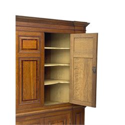 George III and later oak and mahogany banded corner cupboard, moulded cornice over four panelled doors, the door panels inlaid with mahogany bands, projecting square pilasters throughout with applied reeded mouldings, the painted interior fitted with shaped shelves, on moulded plinth base 