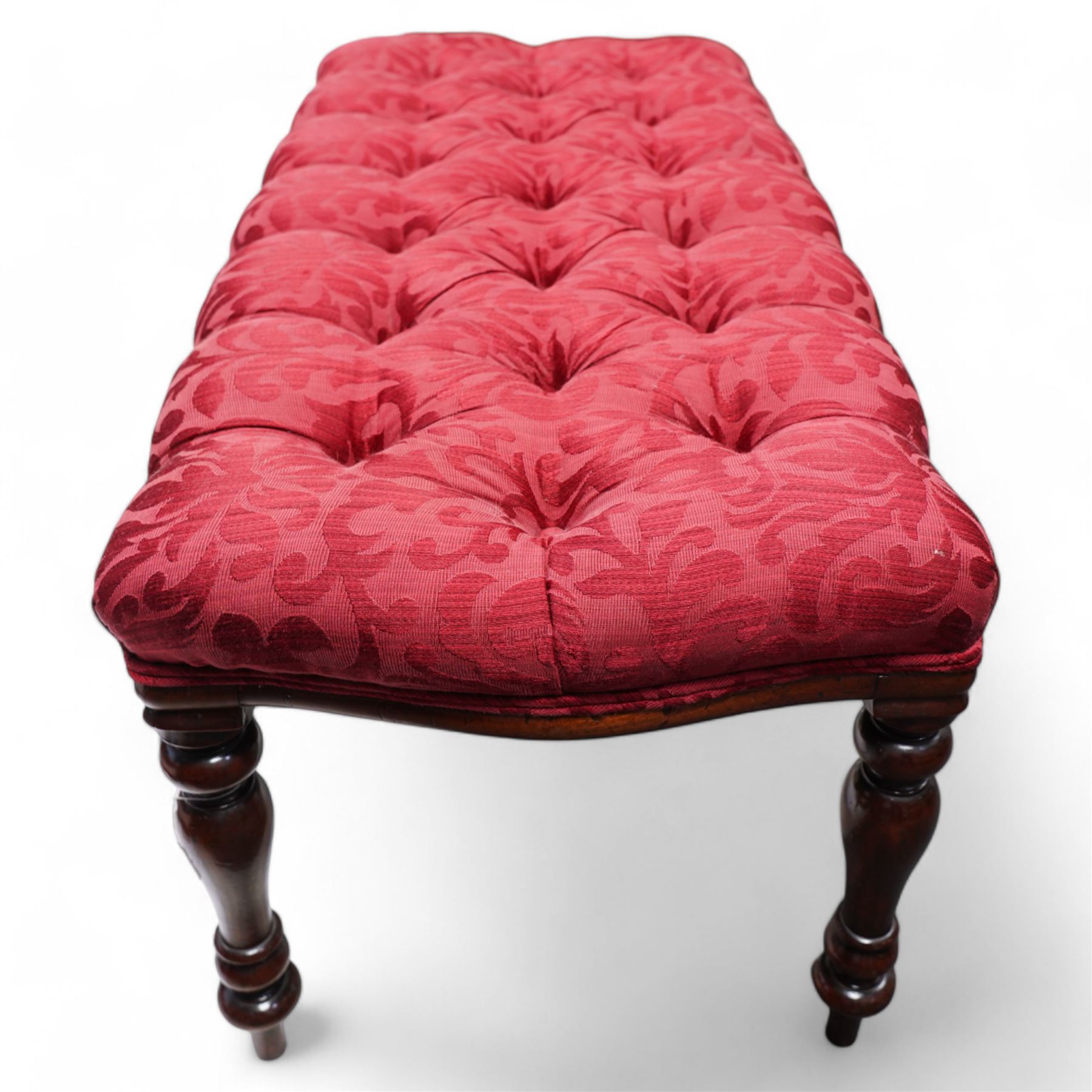 Victorian design mahogany footstool, rectangular form, the seat upholstered in red buttoned fabric with stylised foliate pattern, on turned supports 