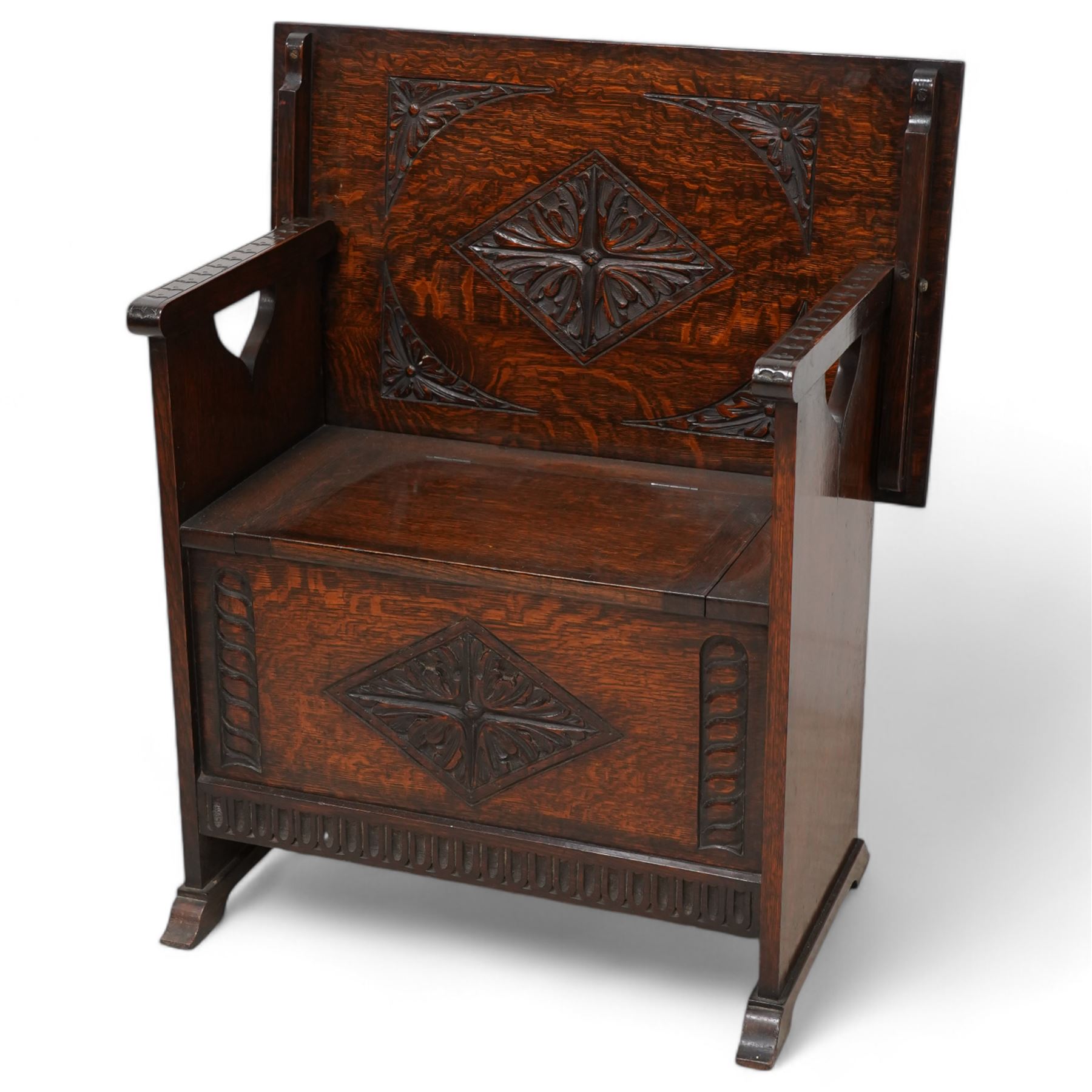 Early-to-mid-20th century carved oak monk's bench, metamorphic top with foliate lozenge carvings, over box seat with hinged lid, arcade carved lower rail on shaped feet