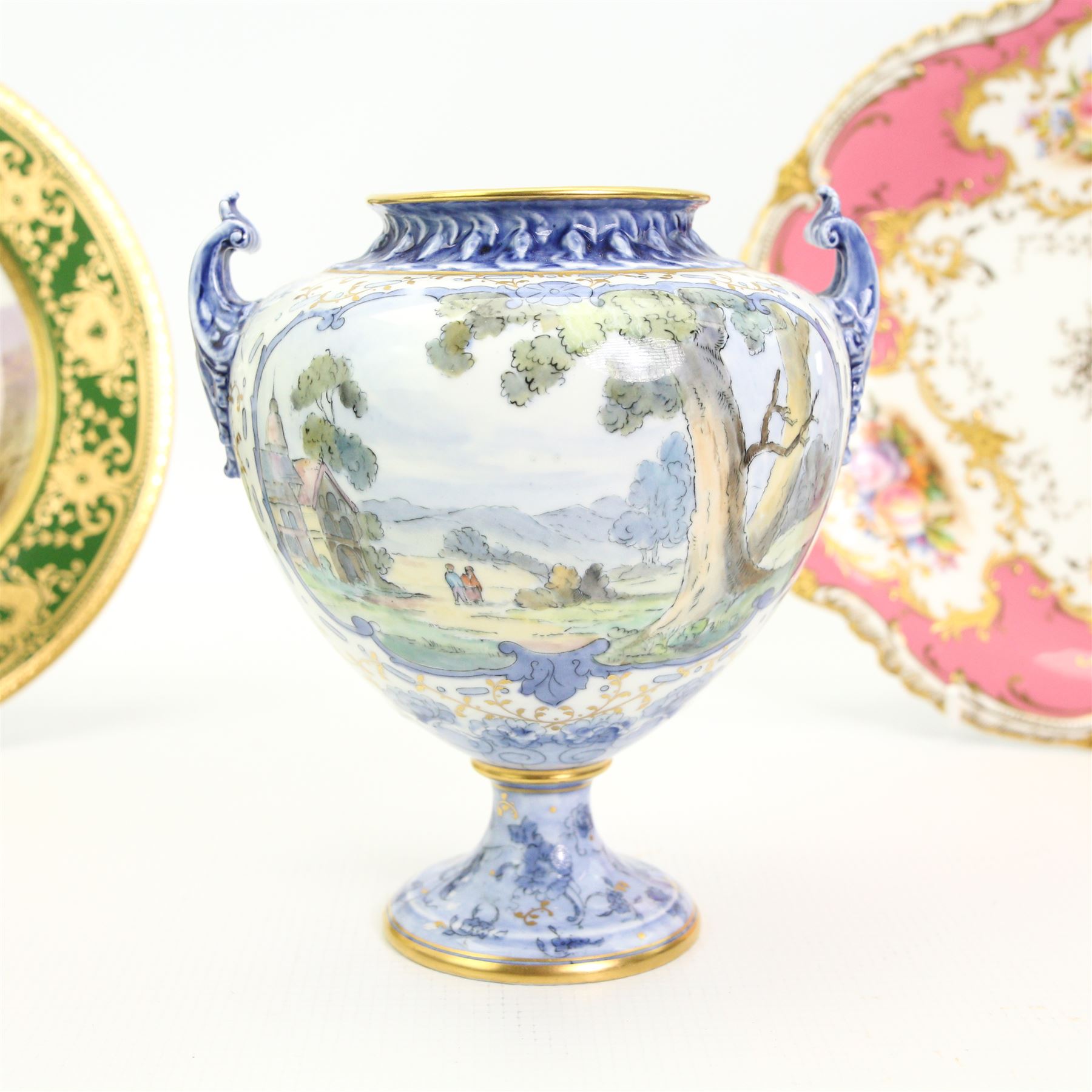 Early 20th century Royal Crown Derby porcelain twin handled vase, circa 1926, the central cartouche with a landscape, H16cm, Coalport cabinet plate centrally painted with a Red Grouse in a Highland landscape, within a green and gilt raised border, D22cm, together with a Coalport dish, hand painted with fruit against a pink and gilt ground (3)