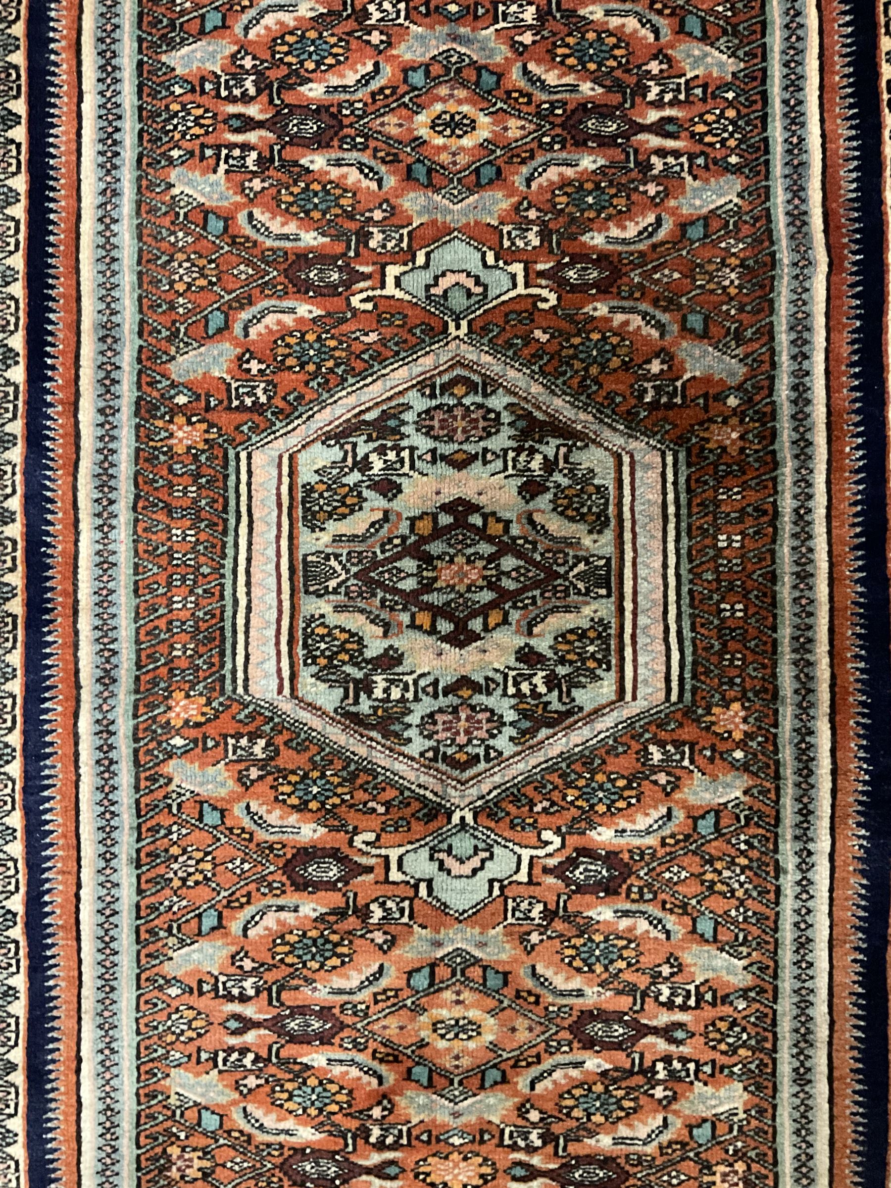 North West Persian Bidjar rug, orange peach ground extended field on indigo ground, decorated with floral Herati motifs, repeating waved border decorated with stylised plant motifs