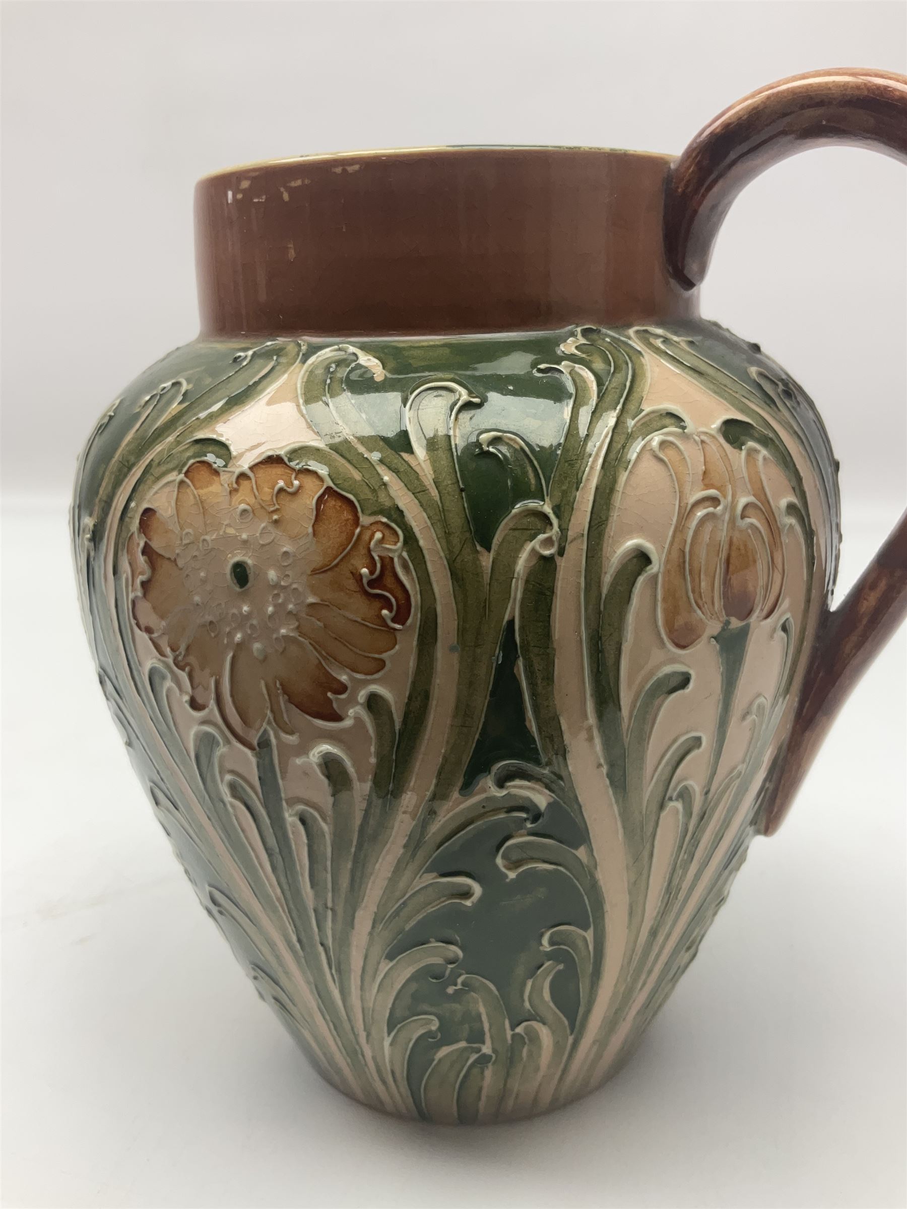 Moorcroft Macintyre Burslem jug, circa 1902, decorated with a motif of stylised flowers amongst scrolling foliage, in shades of brown and green on a peach ground, with printed mark beneath, H16cm