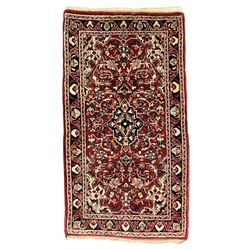 Persian crimson ground rug or mat, field decorated with central medallion and all-over scrolling floral motifs, border with repeating palmettes