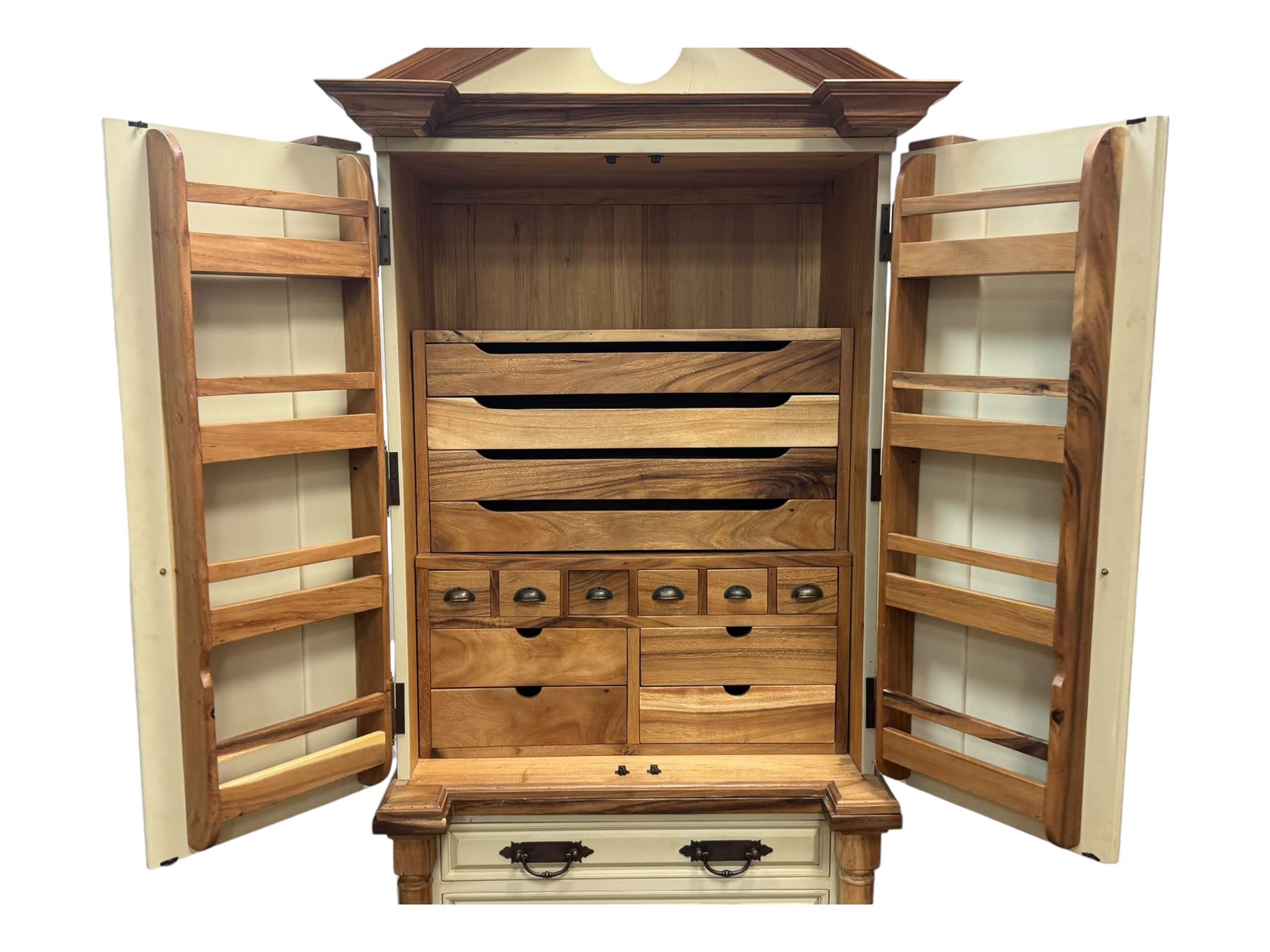 Hardwood and cream painted kitchen larder cupboard, sloped pediment over two panelled doors, the interior fitted with slides, drawers and storage shelves, two long drawers below, mounted by turned pilasters, on metal bound moulded plinth base