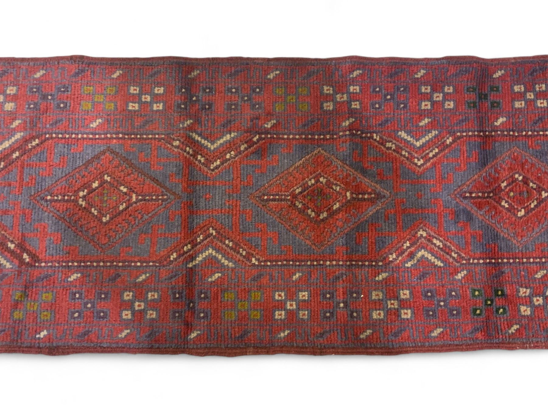 Meshwani crimson ground runner rug, the busy field decorated with four trailing lozenges surrounded by geometric motifs