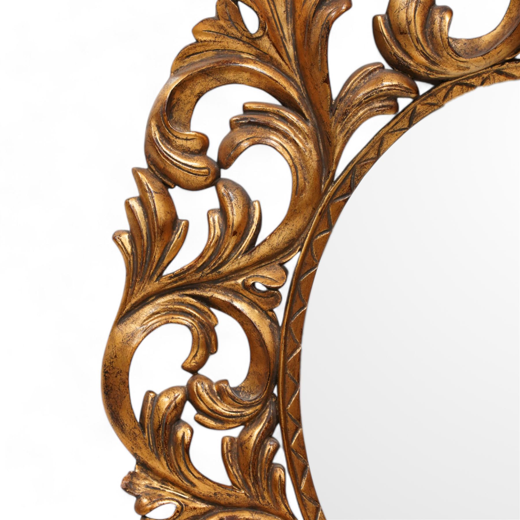 Florentine design gilt wall mirror, bevelled oval mirror plate surrounded by scrolling and interlaced acanthus leaves, curled leaf pediment 