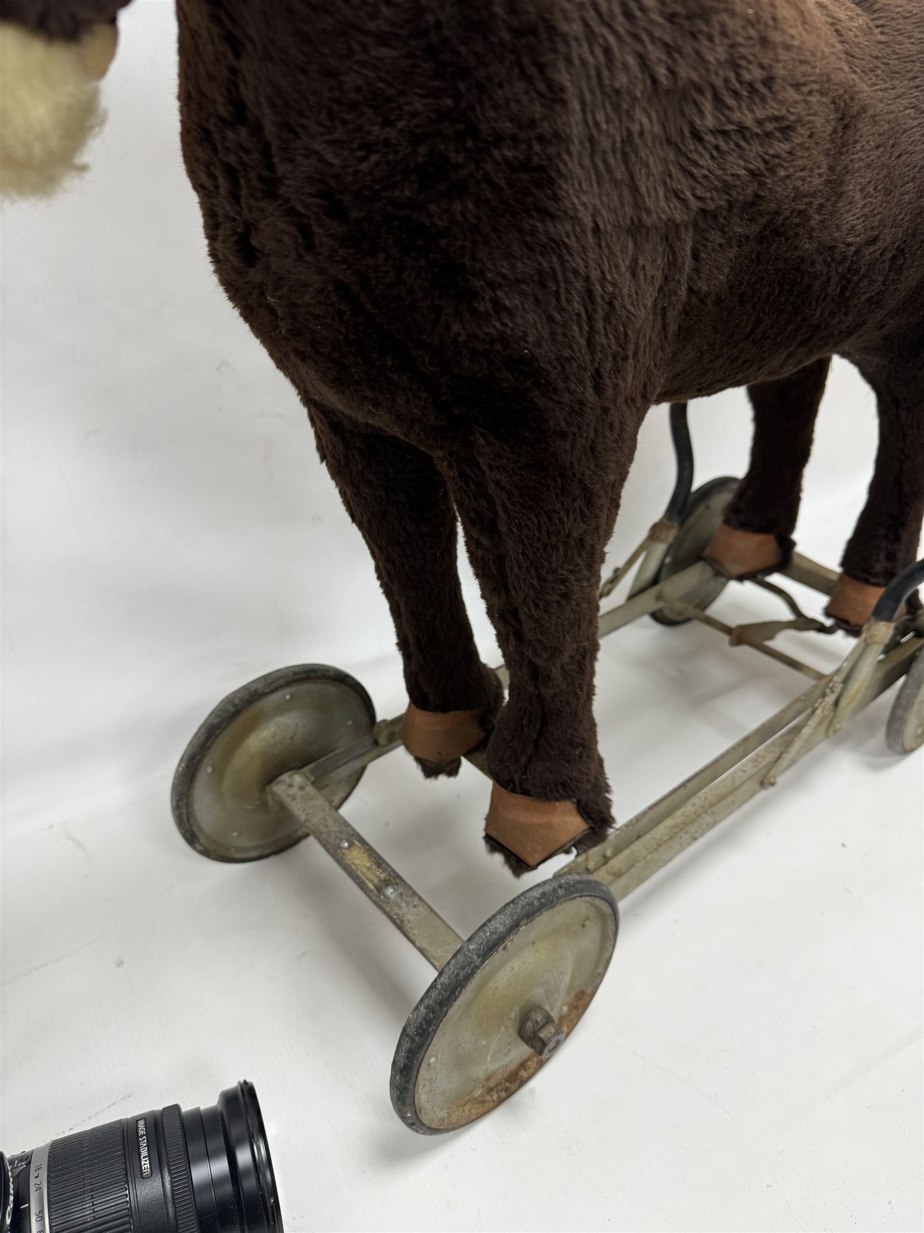 1920s/30s Panurge Pets push-a-long horse, with brown mohair body and white face, horse hair mane and tail and leather hooves, mounted upon a metal with rubber and metal wheels, including handle H71cm