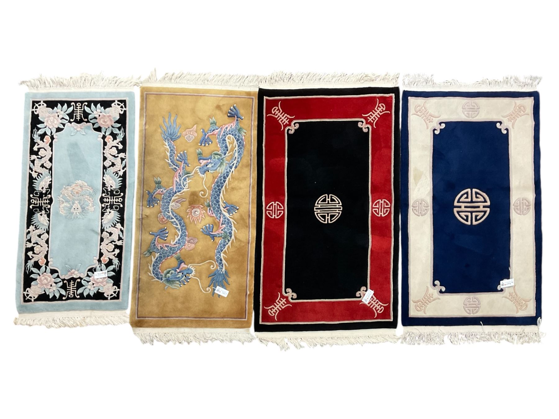 Collection of four Chinese washed woollen rugs - blue ground (153cm x 92cm); red and black ground (156cm x 94cm); light blue ground (138cm x 70cm); gold ground (153cm x 77cm)