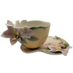 Two Franz teacups and saucers, decorated with flowers, one with matching teaspoon