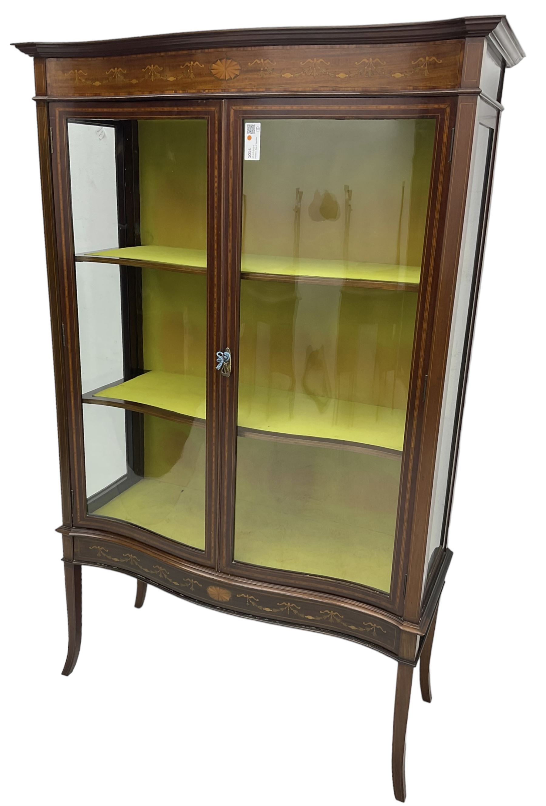 Edwardian inlaid mahogany serpentine display cabinet, projecting moulded cornice over figured frieze inlaid with tailing bellflowers and central fan motif, enclosed by two glazed doors, on square tapering supports with splayed terminals 